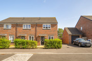Brick end-of-terrace house with hedge and parked car along a residential street.