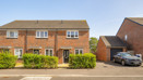 Brick end-of-terrace house with hedge and parked car along a residential street.