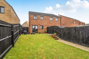 Rear garden with lawn, fencing and row of houses at the back.