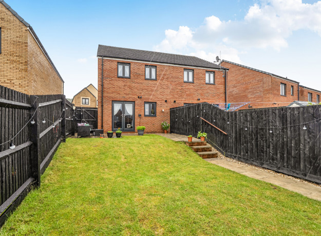 Rear garden with lawn, fencing and row of houses at the back.