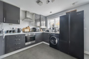 Modern kitchen with grey cabinets, appliances, and black fridge freezer.
