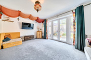 Living room with carpet, sofa, wall-mounted television and patio doors.