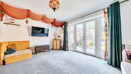 Living room with carpet, sofa, wall-mounted television and patio doors.