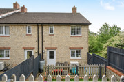 Rear view of brick house with terraced garden with fencing and patio doors.