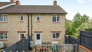 Rear view of brick house with terraced garden with fencing and patio doors.