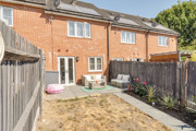 Rear garden with patio area, fencing and red brick house exterior.