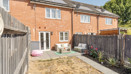 Rear garden with patio area, fencing and red brick house exterior.