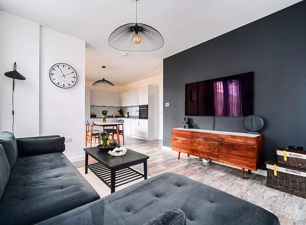 Living room with television, sofa, coffee table and kitchen beyond.