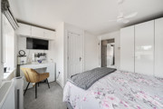 Double bedroom with wardrobes, desk and wall-mounted television.