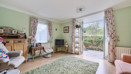 Living room with seating, shelving, windows and patio doors.