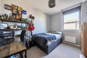 Carpeted bedroom with double bed, desk, shelving and window.