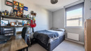 Carpeted bedroom with double bed, desk, shelving and window.