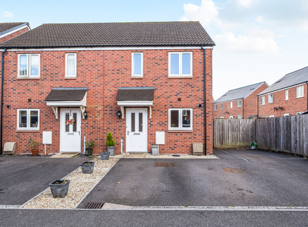 Semi-detached red brick house with driveway and fenced side access.