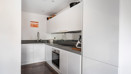 Compact white kitchen with fitted cabinets, worktops and built-in appliances.