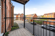 Balcony with metal railings overlooking a street and nearby residential buildings.