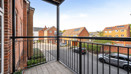 Balcony with metal railings overlooking a street and nearby residential buildings.