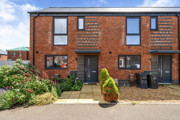 Exterior view of a red brick end of terrace house with a small front garden and path.