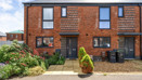 Exterior view of a red brick end of terrace house with a small front garden and path.