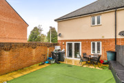 Rear garden with artificial lawn, patio area and fenced boundaries.