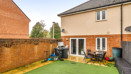 Rear garden with artificial lawn, patio area and fenced boundaries.
