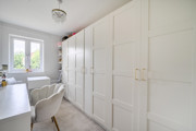 Third bedroom with white wardrobes, desk, chair, and window at the end.