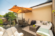 Patio with outdoor seating, a dining table and a large parasol.