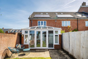 Rear view of house with conservatory and fenced patio garden.
