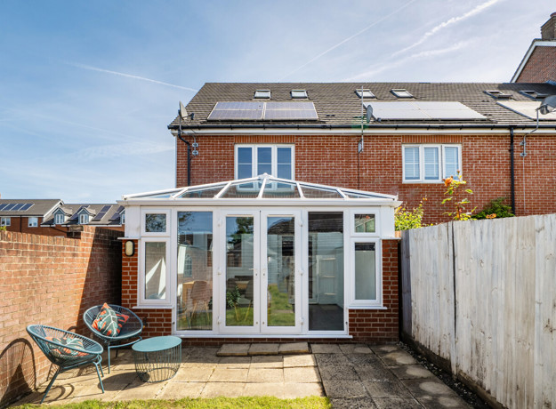 Rear view of house with conservatory and fenced patio garden.
