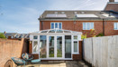 Rear view of house with conservatory and fenced patio garden.