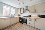 Modern kitchen with white cabinets, light coloured worktops, integrated appliances and window.
