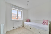 Second bedroom with single bed, white walls, window, and radiator below sill.