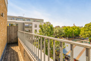 Balcony with metal railing overlooking nearby buildings and trees.
