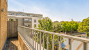 Balcony with metal railing overlooking nearby buildings and trees.