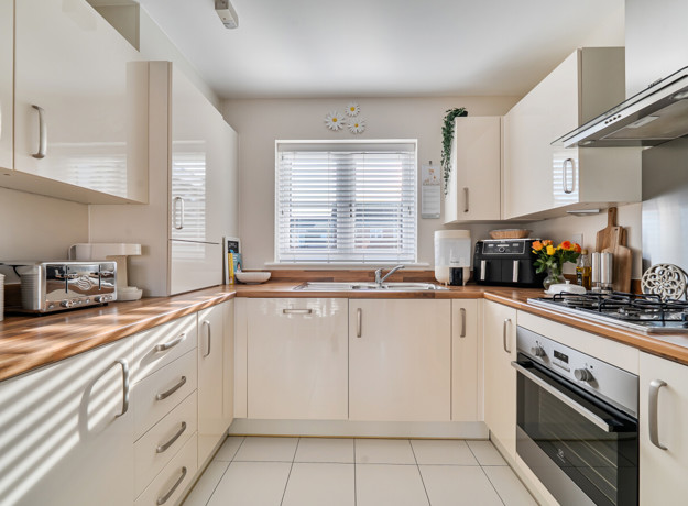 Kitchen with fitted units, worktops, oven, hob and window with blinds.