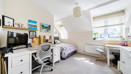 Bedroom with bed, desk, storage units and window.