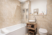 Bathroom with bathtub, glass shower screen, sink and toilet.