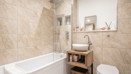 Bathroom with bathtub, glass shower screen, sink and toilet.