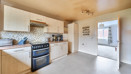 Kitchen with wooden cabinets, tiled floor, and freestanding cooker near a internal door.