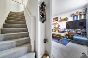 Carpeted staircase with white walls, door leading into living space and landing above.