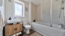 Bathroom with bathtub, shower screen, sink unit, toilet, and frosted window.
