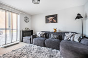 Living room with corner sofa, wall art and floor-to-ceiling window.