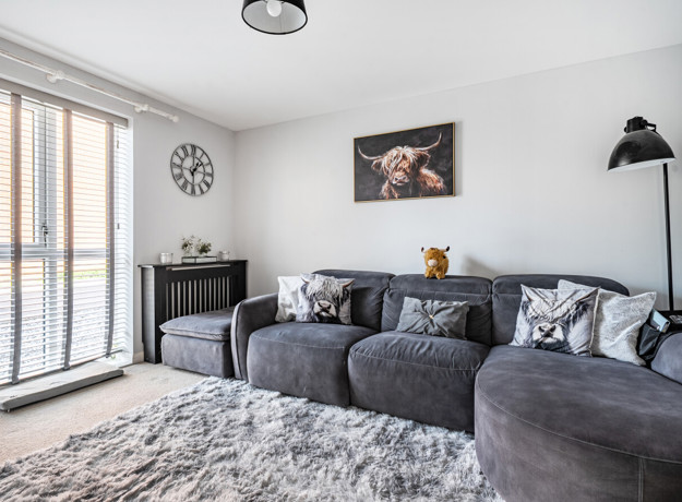 Living room with corner sofa, wall art and floor-to-ceiling window.