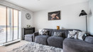 Living room with corner sofa, wall art and floor-to-ceiling window.