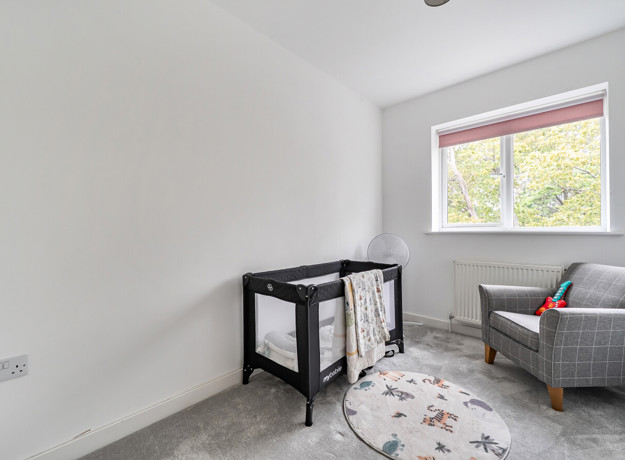 Bedroom with a cot, armchair and window.