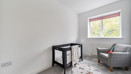 Bedroom with a cot, armchair and window.