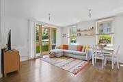 Living area with sofa, table, TV unit, and glass doors to outside.