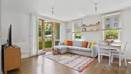 Living area with sofa, table, TV unit, and glass doors to outside.
