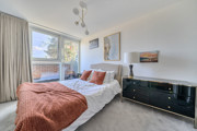 Bedroom with double bed, bedside tables and large window.