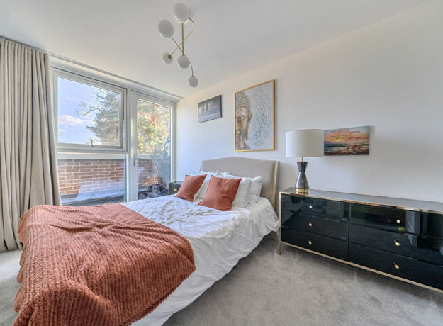 Bedroom with double bed, bedside tables and large window.