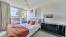 Bedroom with double bed, bedside tables and large window.